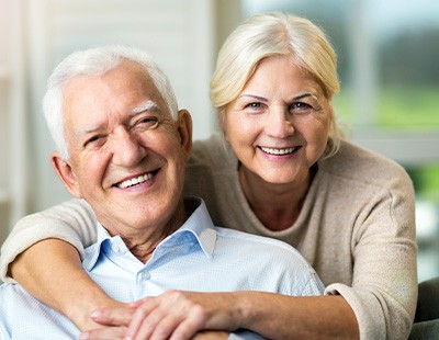 Older couple smiling after completing dental implant post-op instructions in Frederick  